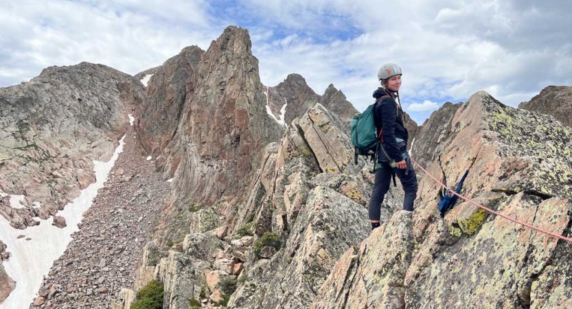 a person wearing safety gear is attached to a rope as a they stand amid a rocky landscape